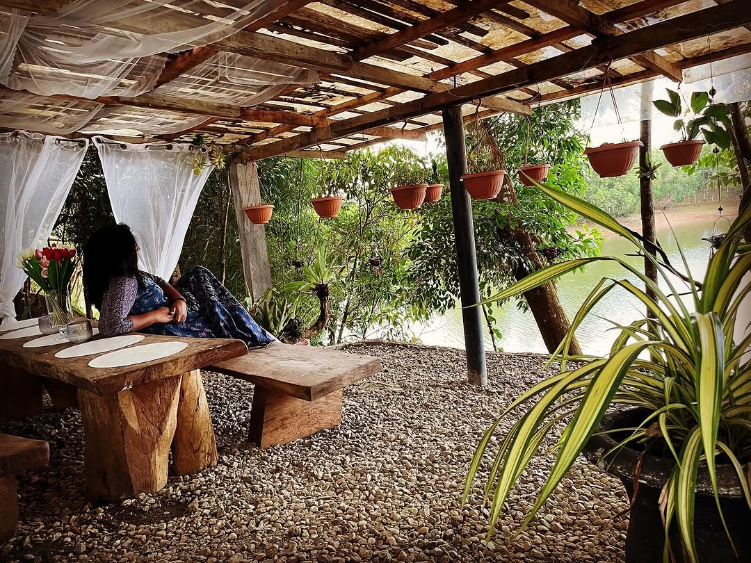 Pavilion lounge pergola with hanging plants, rustic wood benches, and lake visible beyond